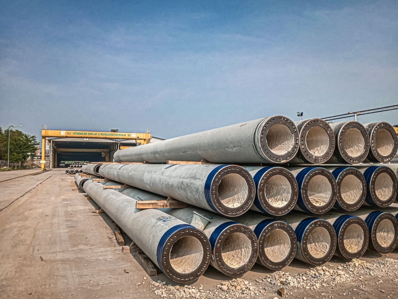 Mastering the First Impression: Your intriguing post title goes here Stacked industrial concrete pipes near a construction area under clear skies.