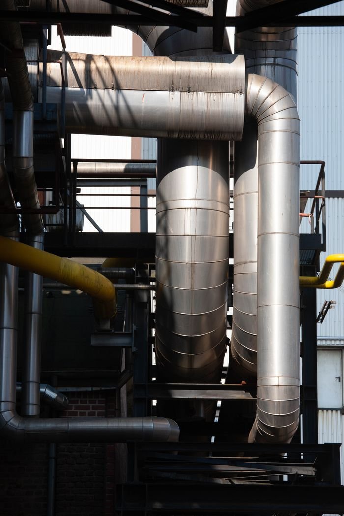 The Art of Drawing Readers In: Your attractive post title goes here Intricate network of stainless steel pipes in an industrial complex under sunlight.